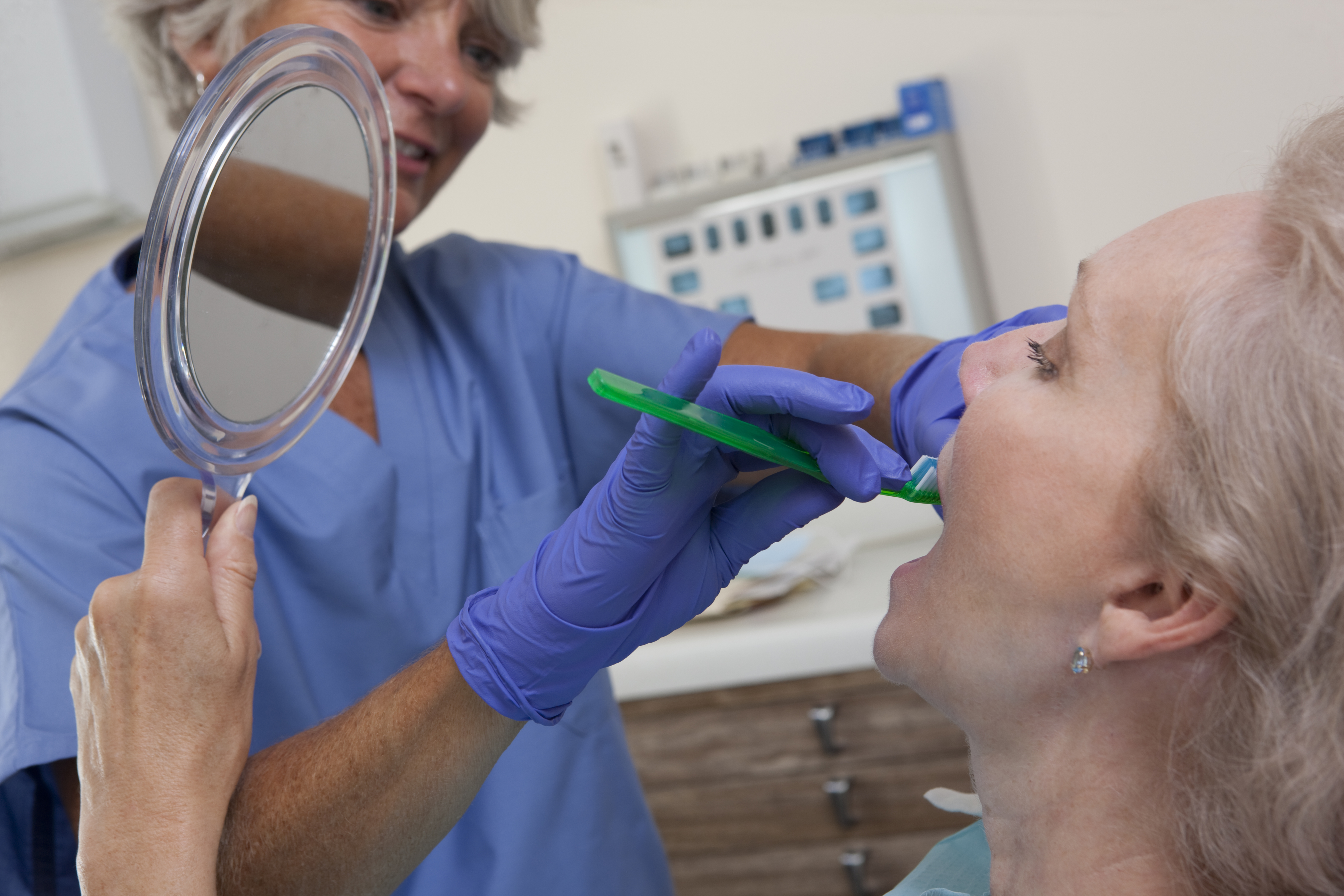 Female dental hygienist brushing the teeth of a patient